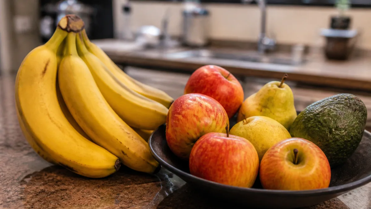 Bananas ao lado de maçãs, peras e abacate em uma cozinha