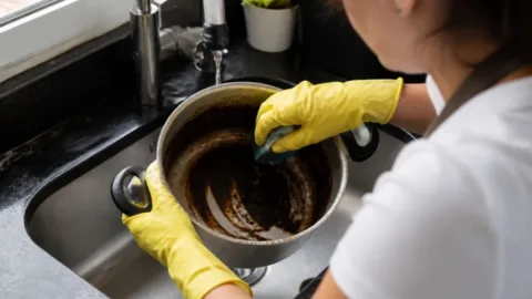 Pessoa limpando uma panela queimada com esponja macia