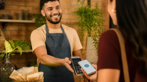 Empreendedor recebendo pagamento por Pix no balcão de uma pequena loja