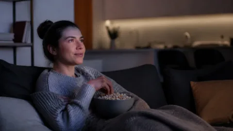 Pessoa assistindo a um filme em casa com tranquilidade