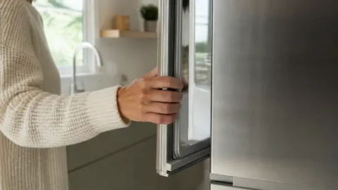 Pessoa abrindo a porta da geladeira na cozinha